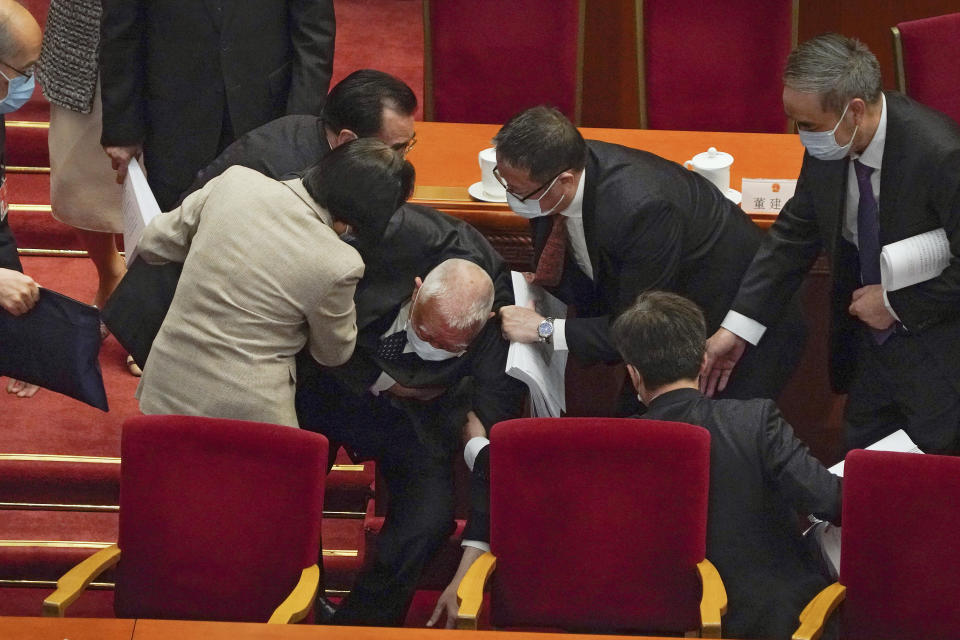 Delegates help former Hong Kong Chief Executive Tung Chee-hwa after he fell following the opening session of China's National People's Congress (NPC) at the Great Hall of the People in Beijing, Friday, March 5, 2021. China's No. 2 leader announced a healthy economic growth target Friday and plans to make this nation self-reliant in technology amid tension with Washington and Europe over trade, Hong Kong and human rights. (AP Photo/Andy Wong)