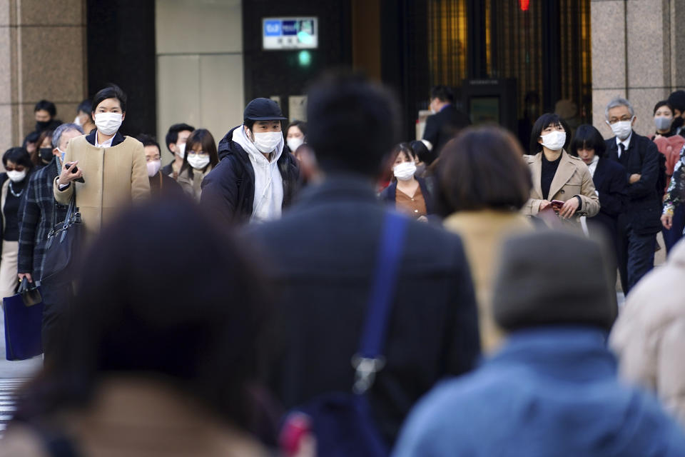 People wearing protective masks to help curb the spread of the coronavirus walk along a pedestrian crossing Thursday, Feb. 25, 2021, in Tokyo. The Japanese capital confirmed more than 340 new coronavirus cases on Thursday. (AP Photo/Eugene Hoshiko)