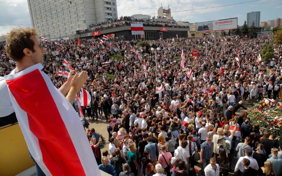 People hold old Belarusian National flags and gather at the place where Alexander Taraikovsky died amid the clashes