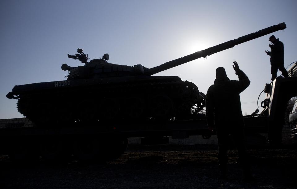 Russian officers gesticulate to the driver of Russian tank T-72B at the Ostryakovo railway station not far from Simferopol, Crimea, Monday, March 31, 2014. Russian tanks T-72B will be stationed on former Ukrainian military bases. (AP Photo/Pavel Golovkin)