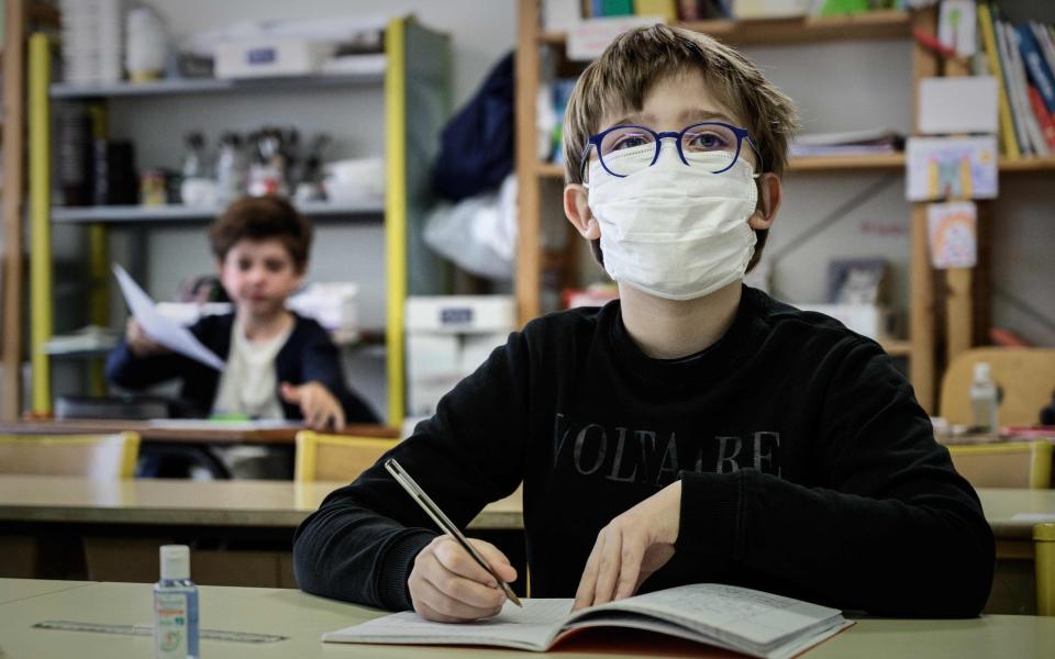 A pupil wearing a facemask attends a class at the private school Institut Sainte Genevieve in Paris - AFP