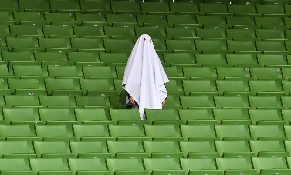 A man dressed as a ghost stands on the empty tribune prior the Europa League round of 16 first leg soccer match between Linzer ASK and Manchester United in Linz, Austria, Thursday, March 12, 2020. The match is being played in an empty stadium because of the coronavirus outbreak. (AP Photo/Kerstin Joensson)