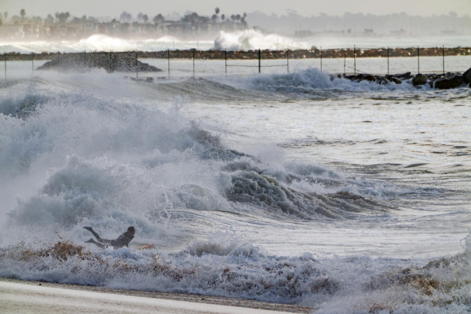 A surfer rides the waves in Seal Beach, Calif., Saturday, Dec. 30, 2023. (AP Photo/Damian Dovarganes)