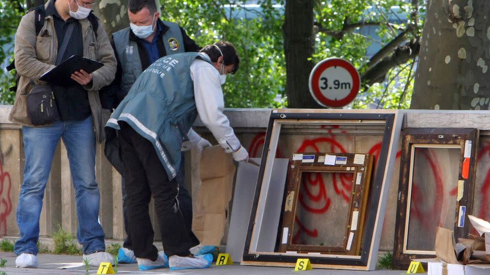 Police officers in Paris search for clues in the frames of the stolen paintings outside the Museum of Modern Art on May 20, 2010. - Jacques Brinon/AP