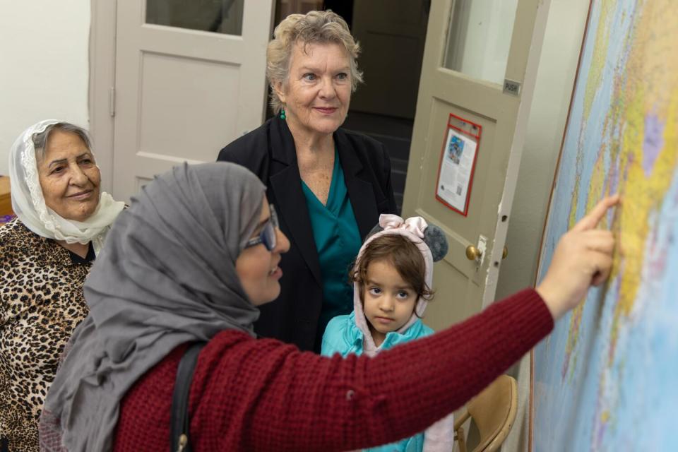 Three women and a child looking at a map.