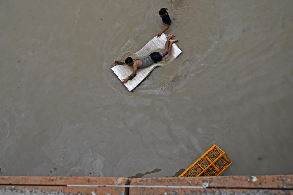 A man floats on thermacol through a flooded street after Yamuna River overflowed due to monsoon rains in New Delhi on July 14, 2023.  / Credit: ARUN SANKAR/AFP via Getty Images