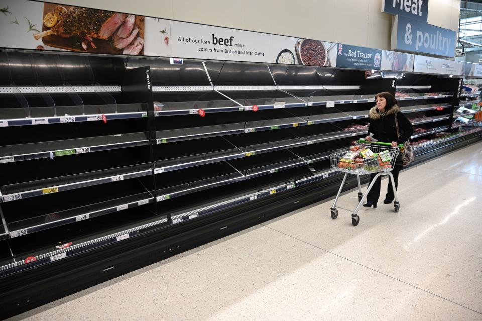 A shopper walks past empty food shelves amidst the novel coronavirus COVID-19 pandemic, in Manchester, northern England on March 20, 2020. - The British prime minister urged people in his daily press conference on March 19 to be reasonable in their shopping as supermarkets emptied out of crucial items -- notably toilet roll -- across Britain. The government said it was temporarily relaxing elements of competition law to allow supermarkets to work together to maintain supplies. (Photo by Oli SCARFF / AFP) (Photo by OLI SCARFF/AFP via Getty Images)