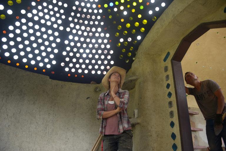 Alexandra Posada (C) pictured with a glass bottle skylight during the building of her house in Choachi, Cundinamarca, Colombia on March 16, 2015