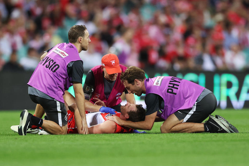 SYDNEY, AUSTRALIA – MARCH 23: Harry Cunningham of the Swans is treated by physiotherapists after being fouled by Peter Wright of the Bombers during the Round 2 AFL match between Sydney Swans and Essendon Bombers at the SCG on March 23, 2024 in Sydney, Australia. (Photo by Mark Metcalfe/AFL Photos/via Getty Images)