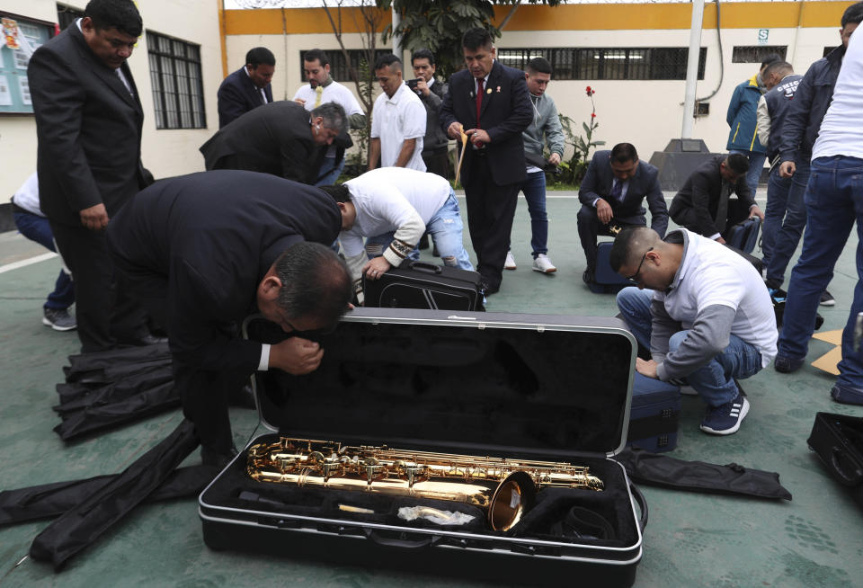 In this July 19, 2019 photo, prison guards search instrument cases in a prison courtyard in Callao, Peru. Peru’s prison service, which normally buys padlocks, keys and shackles, had recently spent more than $150,000 on musical instruments as part of a pioneering project to rehabilitate criminals. (AP Photo/Martin Mejia)