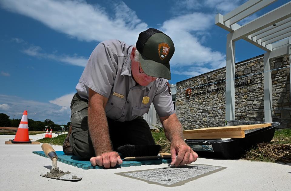 National Park Service employee Douglas Gaylor puts finishing touches on a commemorative stone that's part of the timeline in the sidewalk to the Antietam National Battlefield Visitor Center.