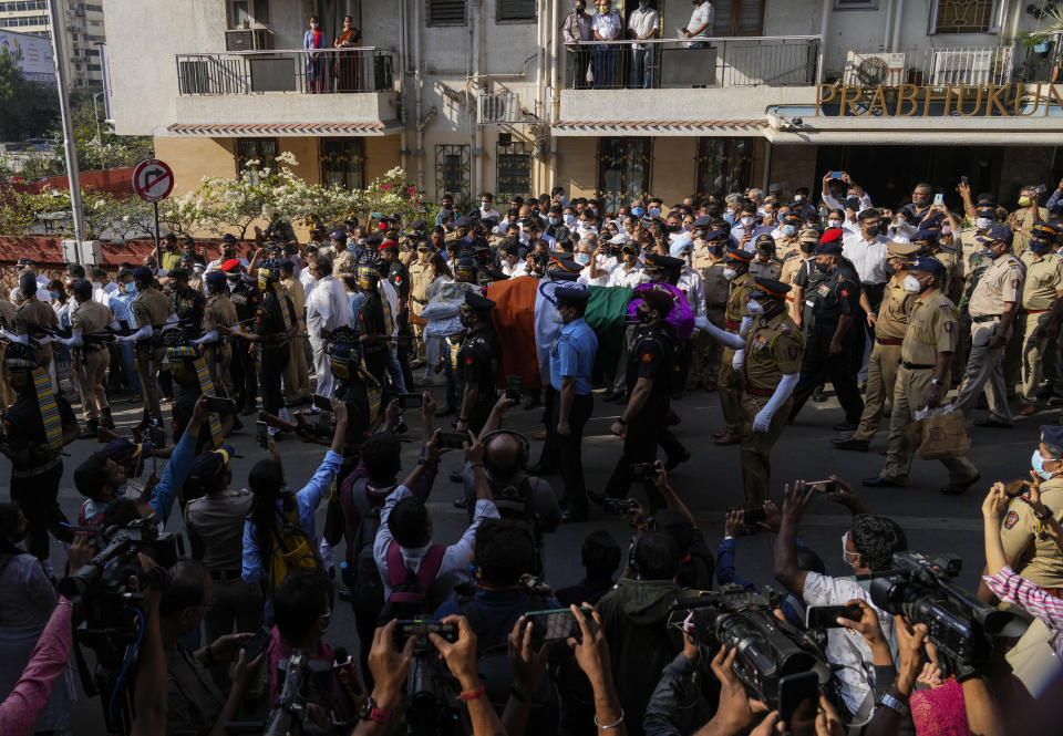 Defense forces and police give a guard of honor as the body of Lata Mangeshkar, lies outside her home in Mumbai, India, Sunday, Feb.6, 2022. The legendary Indian singer with a prolific, groundbreaking catalog and a voice recognized by a billion people in South Asia, died Sunday morning of multiple organ failure. She was 92. (AP Photo/Rafiq Maqbool)