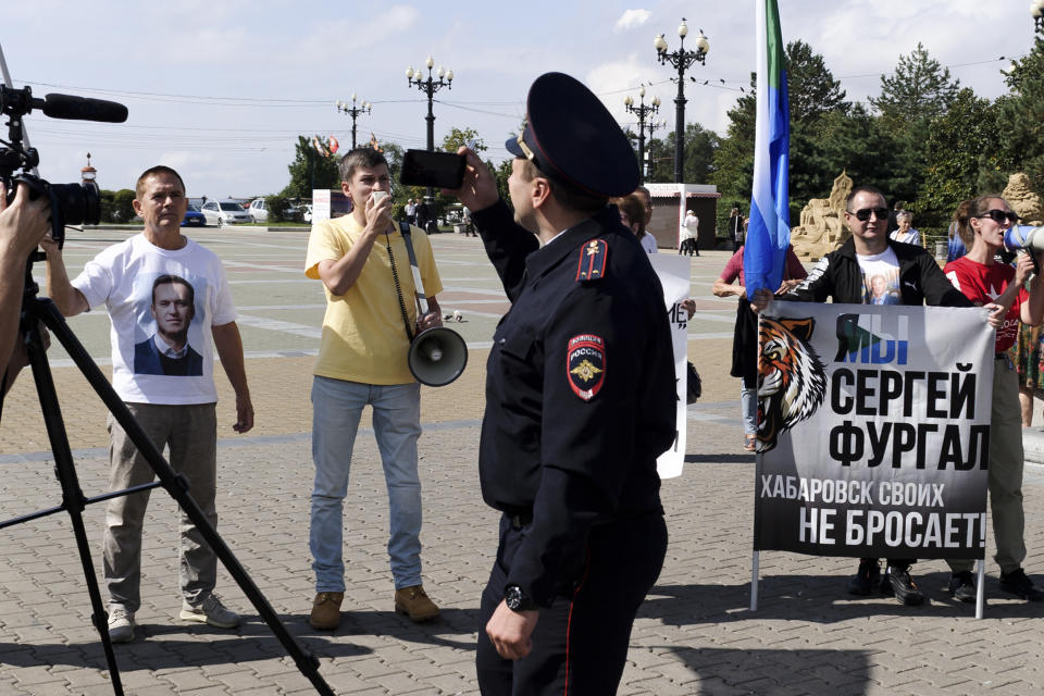 A police officer looks at a group of demonstrators in Khabarovsk, Russia, who had gathered in support of Sergei Furgal, the former governor of the region in the country's Far East, on Saturday, Sept. 11, 2021. A few demonstrators gather in a persistent reminder of the larger protests last year demanding the release of the region's former governor, Sergei Furgal. (AP Photo/Sergei Demidov)