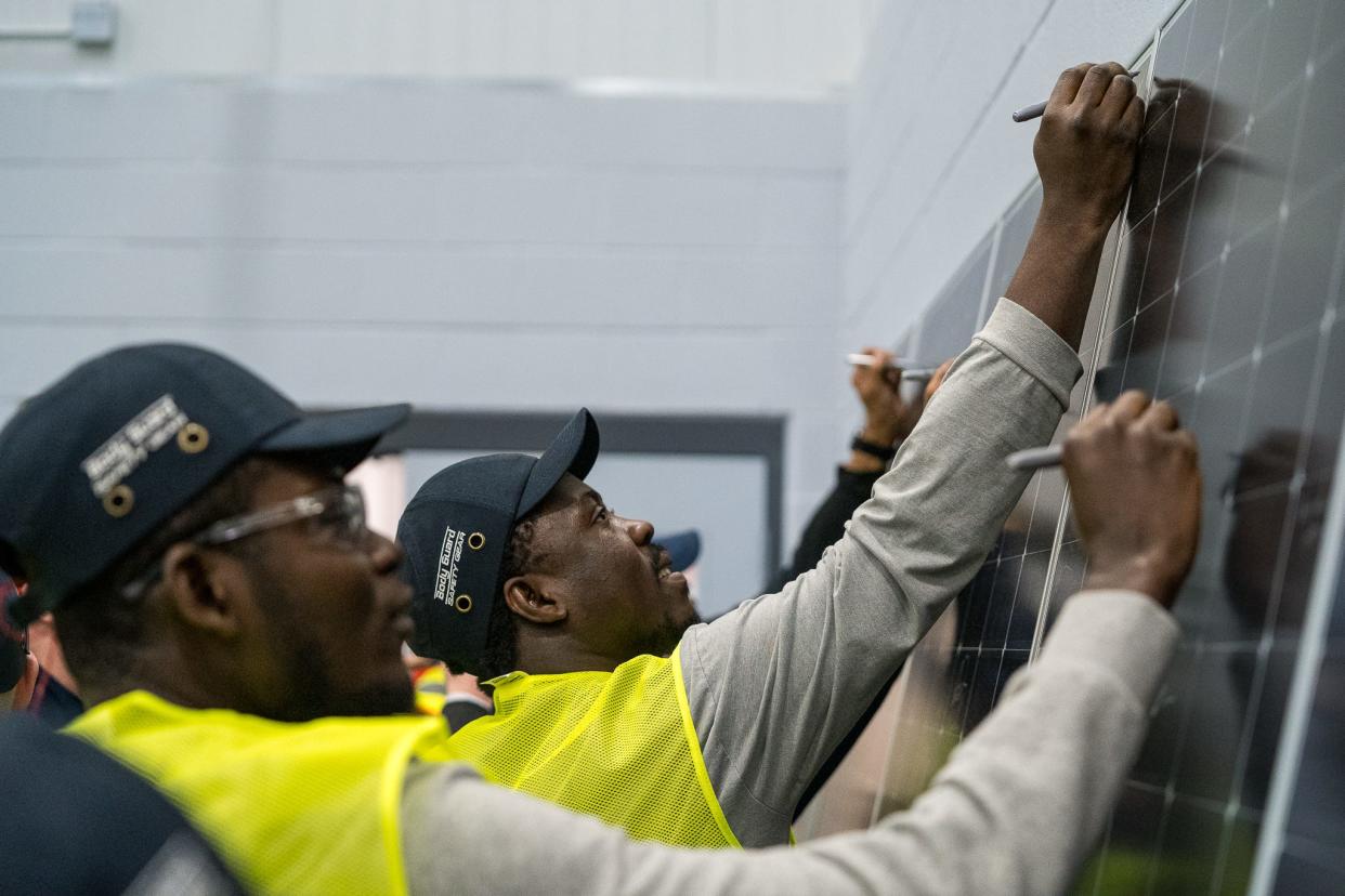 Illuminate USA employees sign their names to solar panels made on Thursday, Feb. 15, which was the first day of production at the new company's Pataskala facility. Illuminate USA will eventually make 9.2 million solar panels annually.