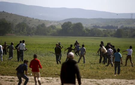 Men throw stones and fight with sticks during a scuffle, which started at a food distribution queue, at a makeshift camp for migrants and refugees at the Greek-Macedonian border near the village of Idomeni, Greece, April 20, 2016. REUTERS/Stoyan Nenov