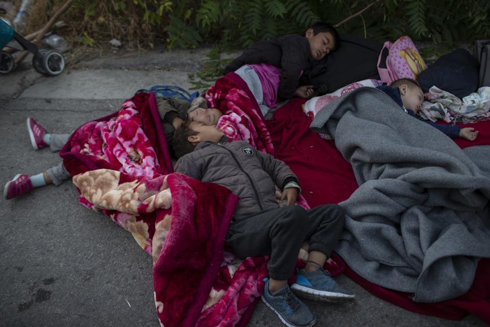 Migrants sleep on the road near the Moria refugee camp on the northeastern island of Lesbos, Greece, Thursday, Sept. 10, 2020. A second fire in Greece's notoriously overcrowded Moria refugee camp destroyed nearly everything that had been spared in the original blaze, Greece's migration ministry said Thursday, leaving thousands more people in need of emergency housing. (AP Photo/Petros Giannakouris)