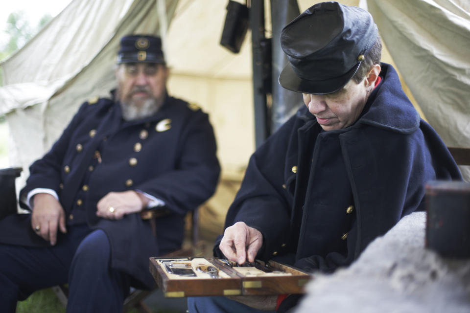 FILE - In this Friday, May 24, 2013 file photo, Richard Baldino, right, accompanied by Dave Morris, both portraying army surgeons with the 2nd Division 11th Corps Army of Potomac, examines an amputation set at the George Spangler Farm that served as a field hospital during the Civil War, in Gettysburg, Pa. As gunshots ravaged the bodies of tens of thousands of soldiers at the Battle of Gettysburg, military doctors responded with a method of treatment that is still the foundation of combat medicine today. (AP Photo/Matt Rourke, File)