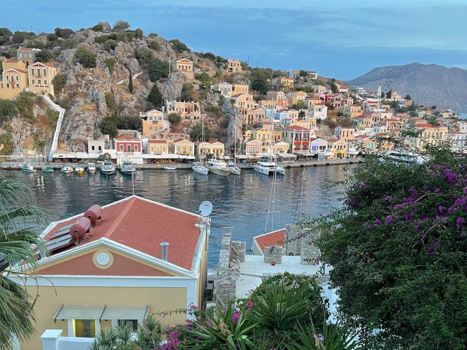 Colorful houses built into a mountain on the water. There are boats docked in the water.