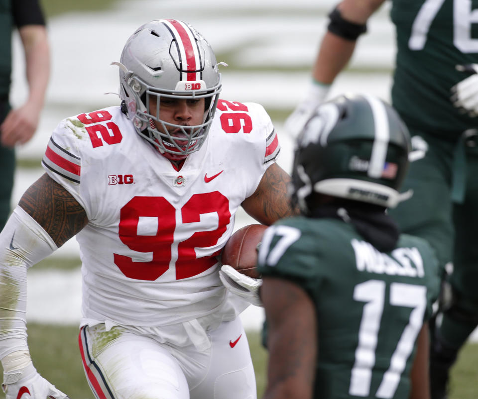 Ohio State's Haskell Garrett, left, scores against Michigan State's Tre Mosley after deflecting and catching a Michigan State pass in the end zone during the first half of an NCAA college football game, Saturday, Dec. 5, 2020, in East Lansing, Mich. (AP Photo/Al Goldis)