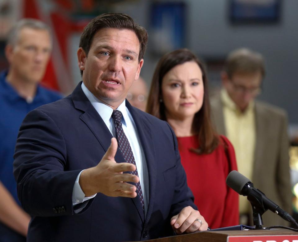 Florida Governor Ron DeSantis flanked by Attorney General Ashley Moody and supporters addresses the media and supporters Thursday, Oct. 28, 2021 in Lakeland Fla. The state of Florida on Thursday sued President Joe Biden's administration over its coronavirus vaccine mandate for federal contractors, opening yet another battleground between Republican Gov. Ron DeSantis and the White House. The lawsuit, announced by DeSantis at a news conference, alleges the president doesnâ€™t have the authority to issue the rule and that it violates procurement law. (Calvin Knight/The Ledger via AP)
