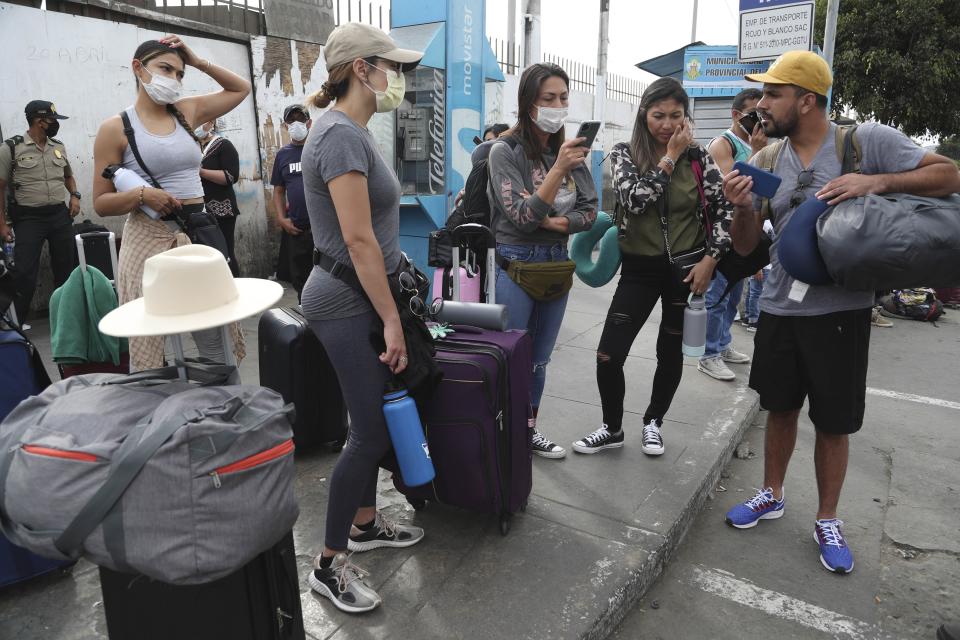 Tourists from the United States wait outside the closed Jorge Chavez International Airport for a member of the U.S. Embassy to escort them to a flight that will fly them back to the U.S., in Callao Peru, Friday, March 20, 2020, on the fifth day of a state of emergency decreed by the government to prevent the spread of the new coronavirus. (AP Photo/Martin Mejia)