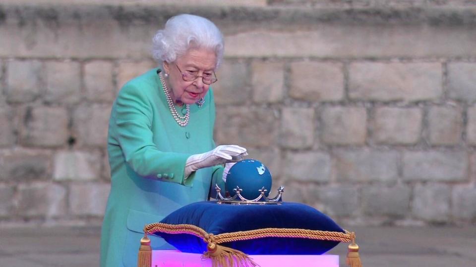 La reina tocando un globo para encender el 