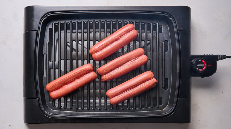 hot dogs cooking on grill