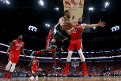 A basketball player passes the ball to another player.