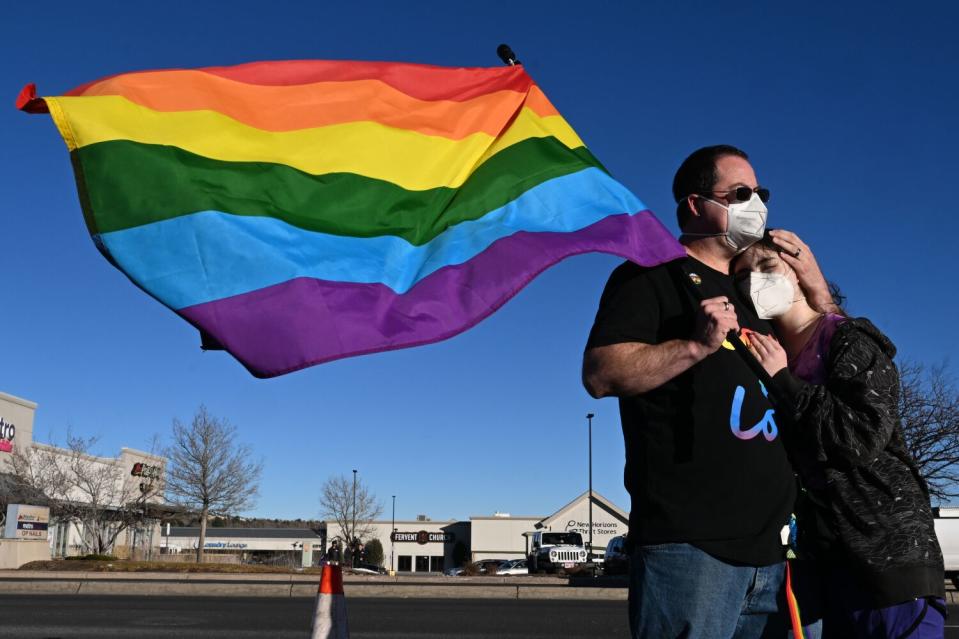 A man and girl stand near a rainbow flag