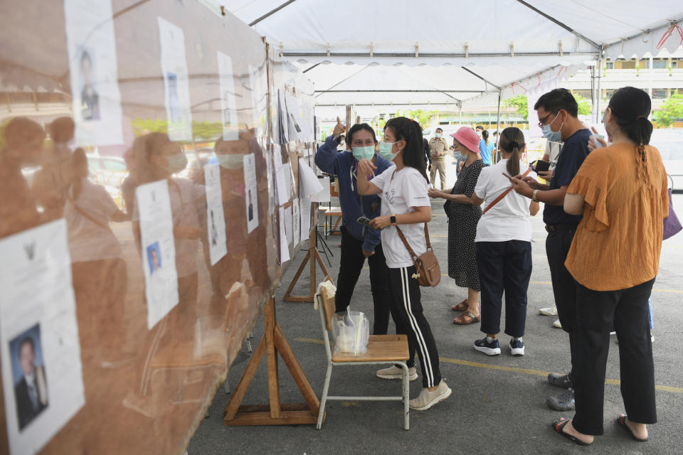 A woman looks for her name prior to casting her ballot in Bangkok's gubernatorial election at a polling station in Bangkok, Thailand, Sunday, May 22, 2022. Residents of the Thai capital Bangkok voted Sunday to elect a new governor, in a contest whose results will be seen as a measure of the strength of the government of Prime Minister Prayuth Chan-ocha. (AP Photo/Thanachote Thanawikran)