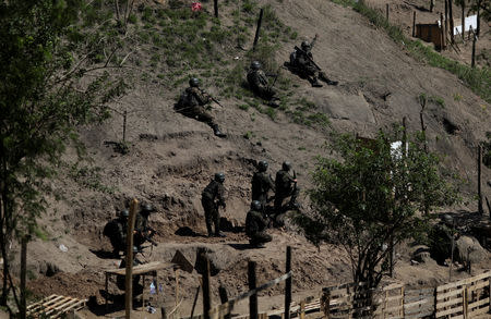 Brazilian Army soldiers take cover during a shootout with drug gangs during an operation in Alemao slums complex in Rio de Janeiro, Brazil August 20, 2018. REUTERS/Ricardo Moraes