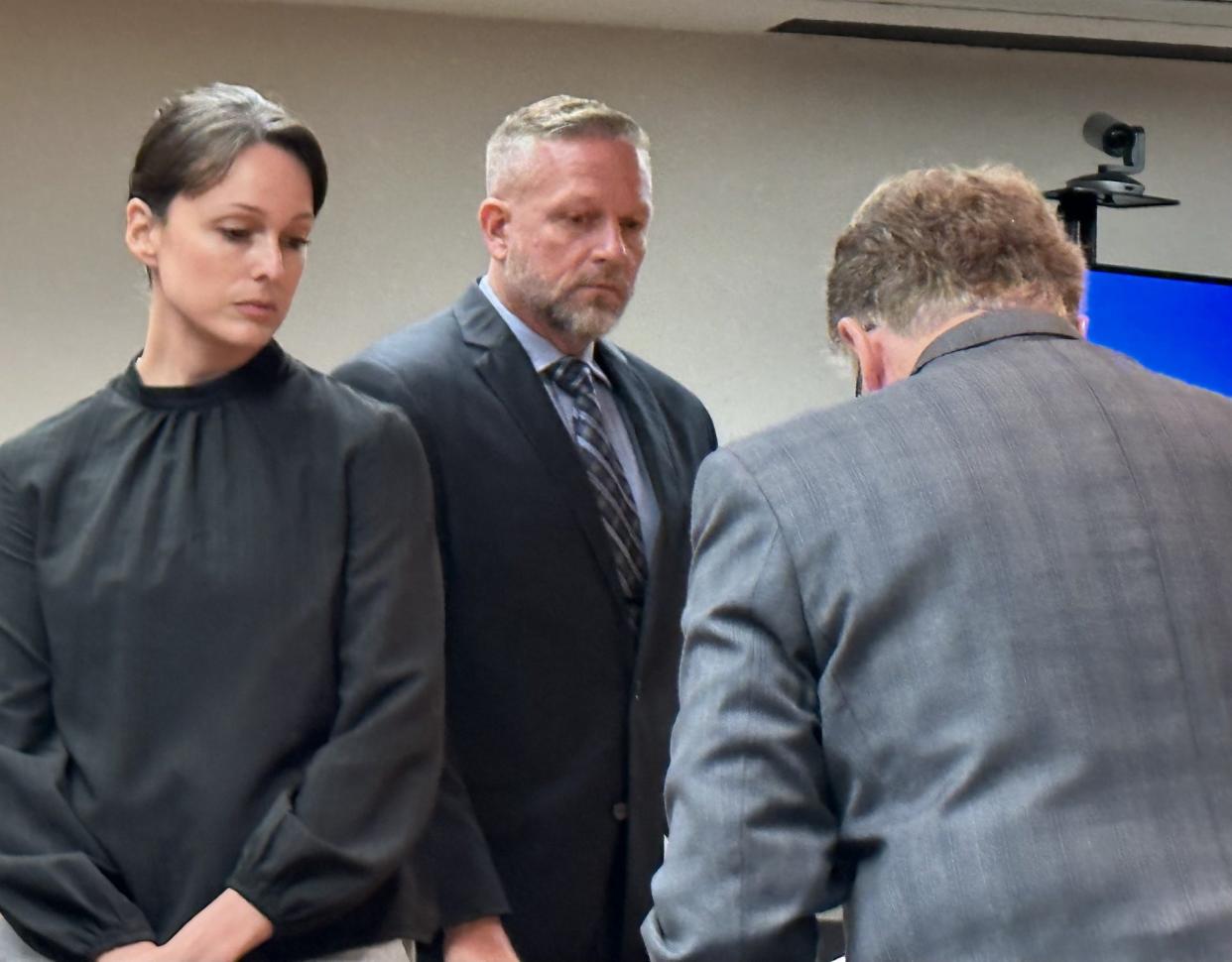 Daytona Beach Shores police Sgt. Jessica Long and Lt. Michael Schoenbrod wait for their attorney, Michael Lambert, right, to collect his notes following a 45-minute hearing in Volusia Circuit Court on Monday, July 17, 2023. They were petitioning a judge to seal all records in an investigation into their jailing of their 3-year-old son for potty training lessons on two occasions last October.