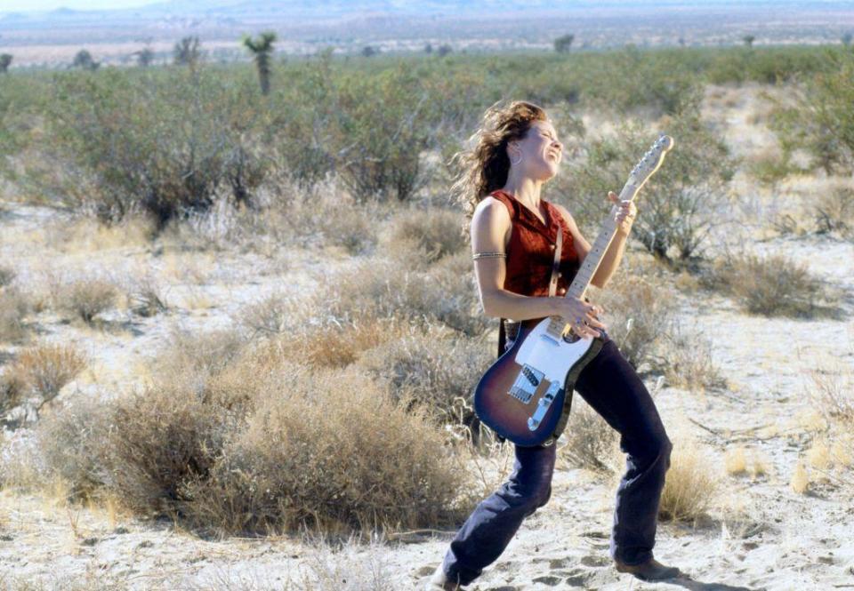 Sheryl Crow plays her guitar in the desert