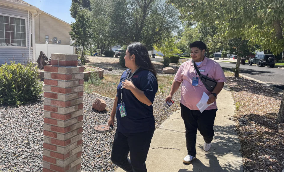 Julia Madera and Domanic Castillo, attendance advocates from Northridge High School, approach the home of three high school students who missed the first five days of school (Ann Schimke/Chalkbeat)