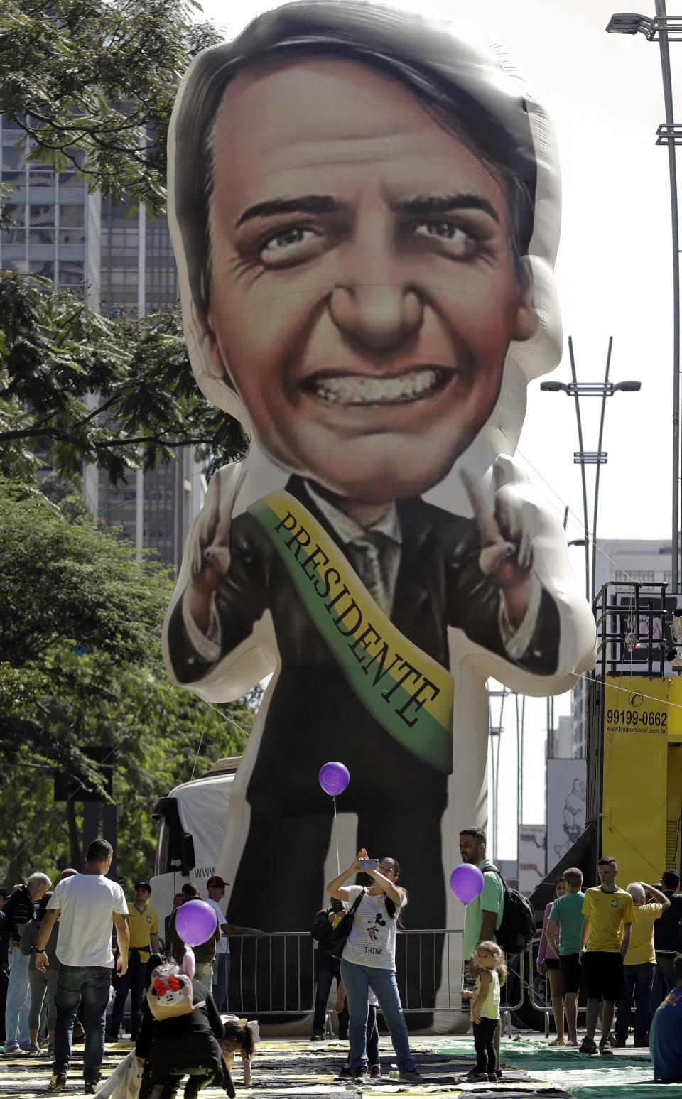 Supporters of Brazil's President Jair Bolsonaro gather around a large, inflatable doll in his image during a rally in his favor along Paulista Avenue in Sao Paulo, Brazil, Sunday, May 26, 2019. The pro-Bolsonaro rally follows anti-government protests against education budget cuts as the leader also battles an uncooperative Congress, a family corruption scandal and falling approval ratings after five months in office. (AP Photo/Andre Penner)