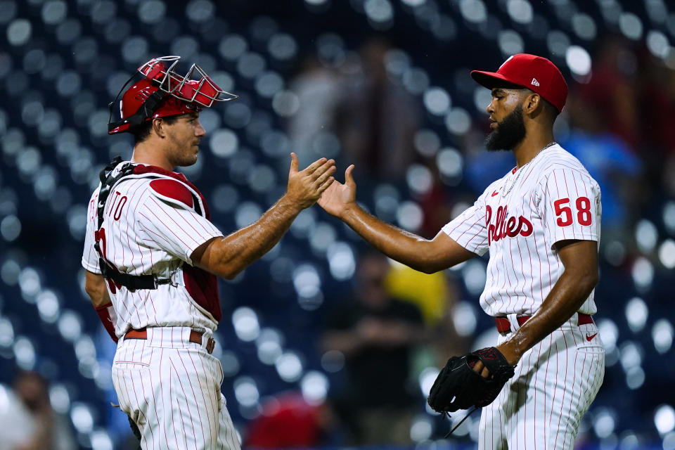 Philadelphia Phillies catcher J.T. Realmuto, left, and relief pitcher Seranthony Dominguez celebrate the team's 4-1 win in a baseball game against the Miami Marlins, Tuesday, Aug. 9, 2022, in Philadelphia. (AP Photo/Matt Rourke)
