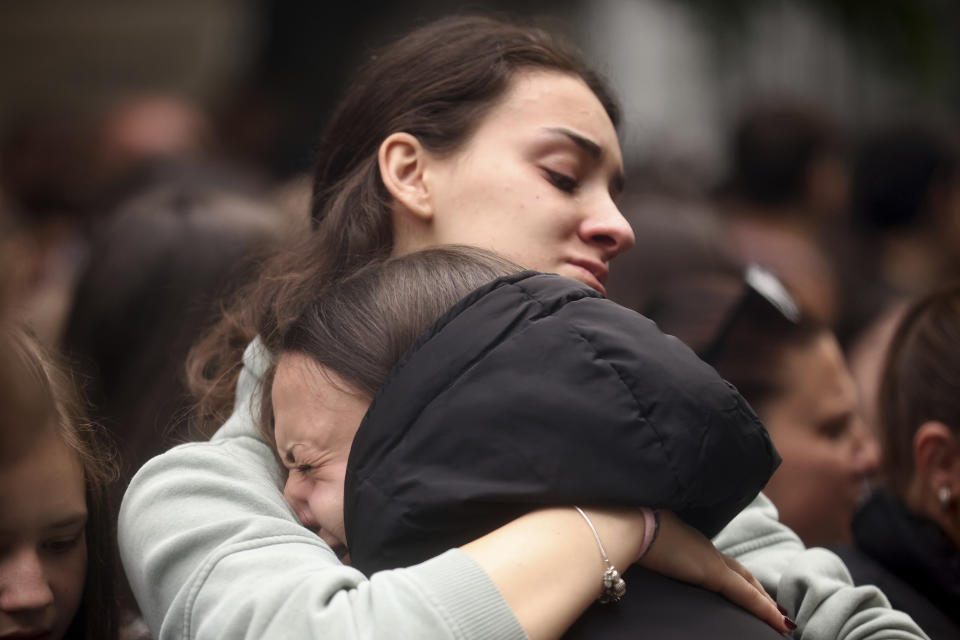 Women cry as people light candles for the victims near the Vladislav Ribnikar school in Belgrade, Serbia, Thursday, May 4, 2023. A 13-year-old who fire Wednesday at his school in Serbia's capital. He killed eight fellow students and a guard before calling the police and being arrested. Six children and a teacher were also hospitalized. (AP Photo/Armin Durgut)