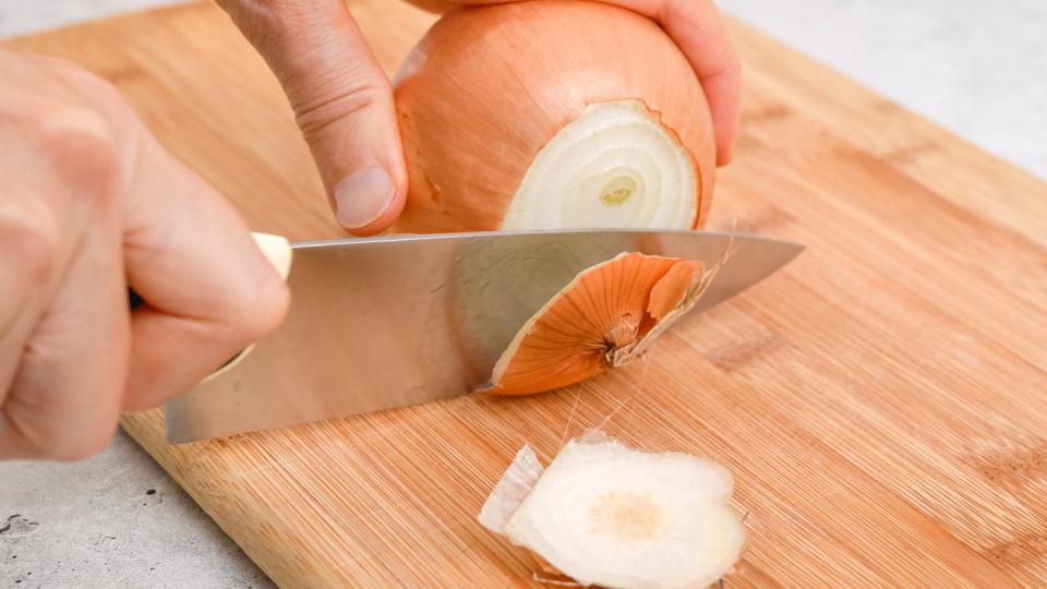 peeling and cutting white onion on a cutting board vegetable soup recipe ingredients close up