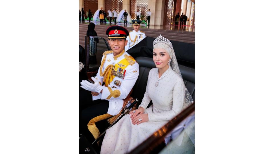 Princess Anisha and husband Prince Mateen pose in their wedding day outfits while in a carriage 