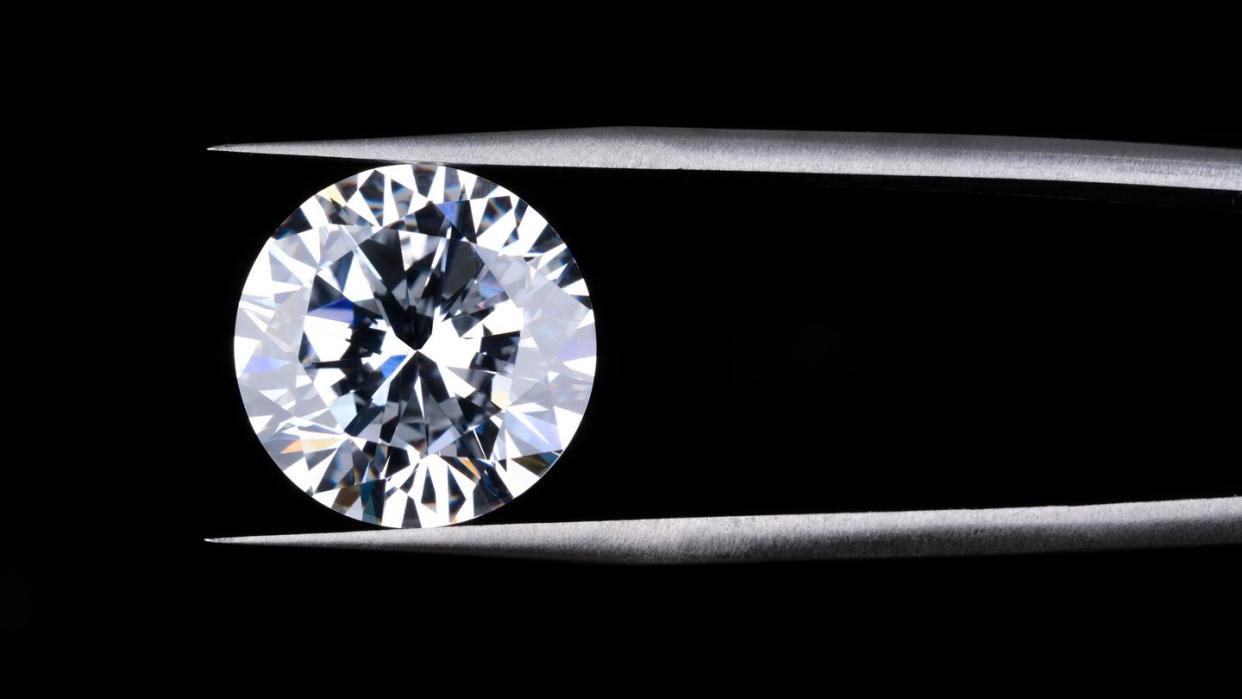 round diamond clamped by tweezers