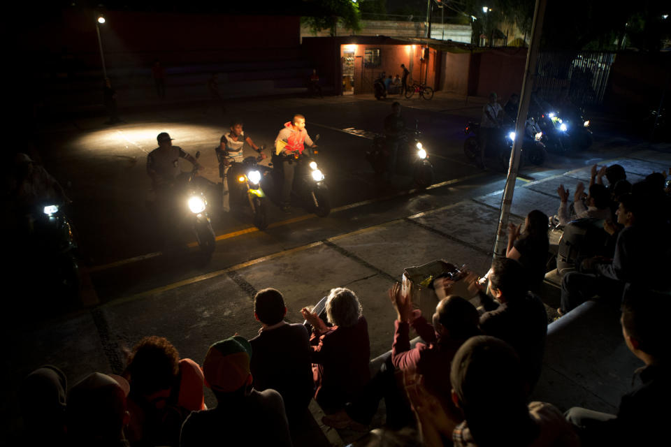 In this April 11, 2014 photo, visitors applaud as motorcycle drivers from Tepito perform a synchronized ride at the conclusion of a theater project showcasing the lives of residents of the troubled neighborhood in Mexico City. The project, titled "Safari in Tepito" has provided employment for some residents, such as the motorcycle drivers. (AP Photo/Rebecca Blackwell)