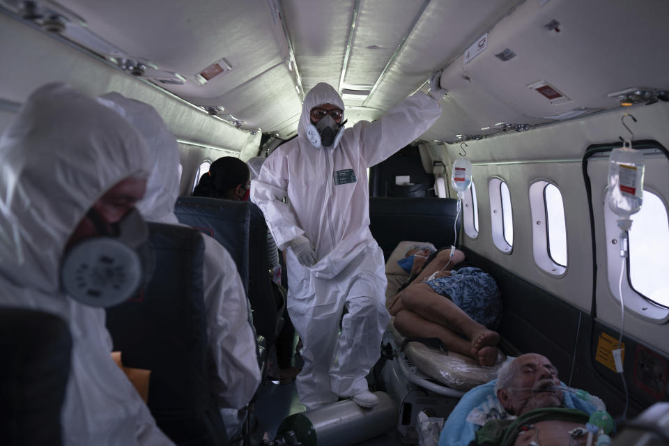 Nurse Janete Vieira, center, and Doctor Daniel Siqueira monitor COVID-19 patients onboard an aircraft as they are transferred from Santo Antônio do Içá to a hospital in Manaus, Brazil, Tuesday, May 19, 2020. The virus has spread upriver from Manaus, creeping into remote riverside towns and indigenous territories to infect indigenous tribes. (AP Photo/Felipe Dana)