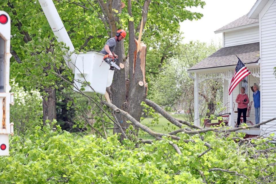 Jason Stickney cuts down a 100-year-old tree in front of the family home of Martin and Mary Aborski on Saturday, May 21, 2022. A tornado touched down destroying several homes and severely damaging others.