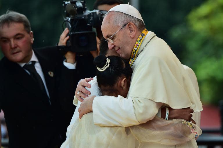 Pope Francis (R) embraces two children, including 12-year-old Glyzelle Palomar (2nd R), during his visit to the University of Santo Tomas in Manila on January 18, 2015