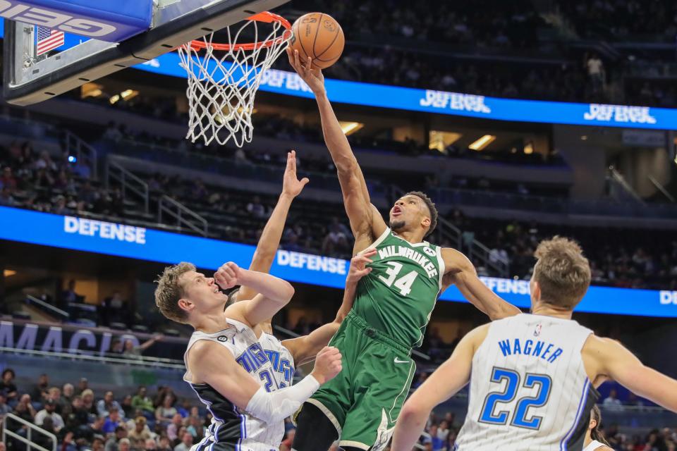 Bucks forward Giannis Antetokounmpo scores between the Wagner brothers, Moritz (left) and Franz, of the Magic during the second half Monday.