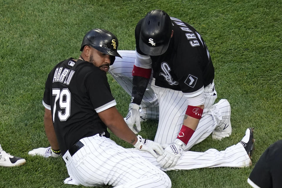 Chicago White Sox's Jose Abreu sits on the ground near home plate as Yasmani Grandal looks at his left knee after Abreu ended up on the ground after Jake Lamb scored during the first inning of a baseball game against the Toronto Blue Jays Wednesday, June 9, 2021, in Chicago. Abreu stayed in the game. (AP Photo/Charles Rex Arbogast)