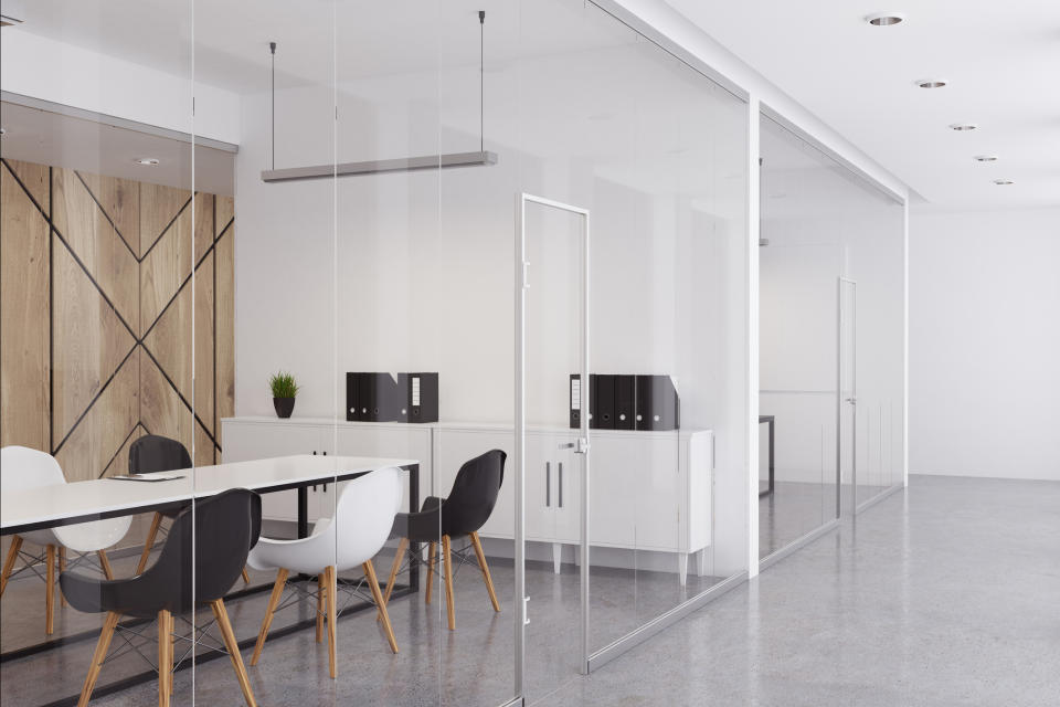 Side view of a glass-enclosed conference room filled with contemporary office furniture.