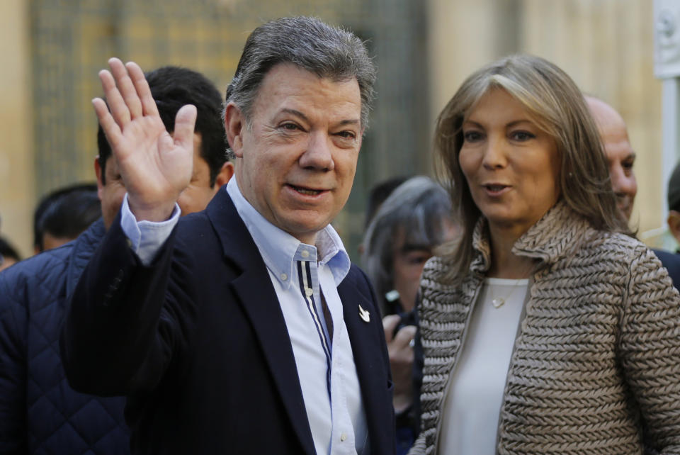 Colombia's President Juan Manuel Santos waves to journalists next to his wife first lady Maria Clemencia Rodriguez as they leave a voting center after voting in legislative elections in Bogota, Colombia, Sunday, March 9, 2014. (AP Photo/Fernando Vergara)