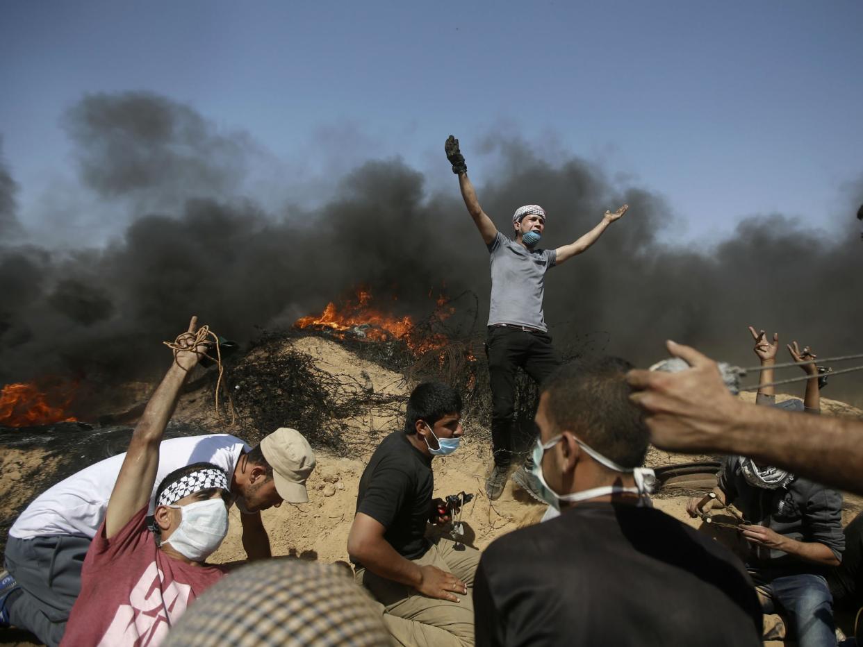 Palestinians take cover near the Gaza Strip's border with Israel during a protest in the Gaza Strip: AP Photo/Adel Hana