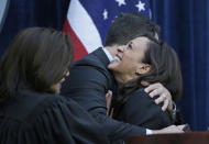 FILE - In this Jan. 5, 2015, file photo California Attorney General Kamala Harris is embraced by her husband, Douglas Emhoff, after taking the oath of office as state Supreme Court chief justice Tani Cantil-Sakauye looks on at the Crocker Art Museum in Sacramento, Calif. (AP Photo/Eric Risberg, File)